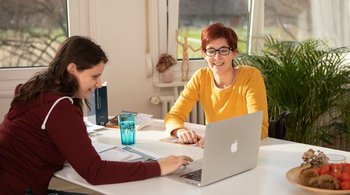 Eine Frau im Rollstuhl wird von einer Fachperson für Sozialversicherung beraten