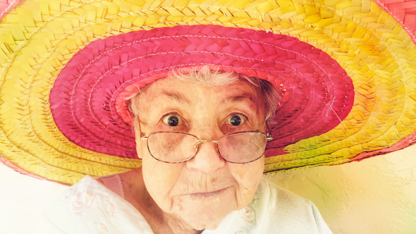 Frau im AHV-Alter mit rot-gelbem Strohhut